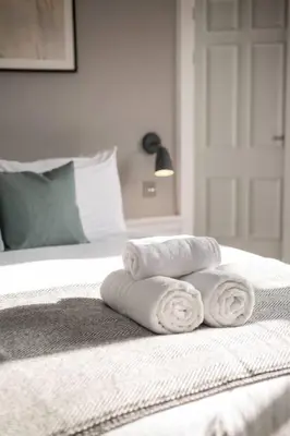 a pile of towels sitting on top of a bed at JOIVY Spacious Apartment close to Princes Street in Edinburgh