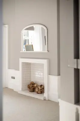 a white room with a fireplace and a mirror at JOIVY Spacious Apartment close to Princes Street in Edinburgh