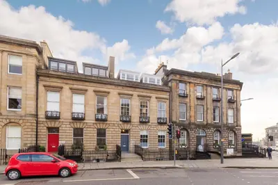 a red car parked in front of a building at JOIVY Spacious Apartment close to Princes Street in Edinburgh