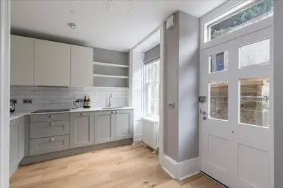 a kitchen with white cabinets and a white door at JOIVY Luxurious Home near Haymarket Station in Edinburgh