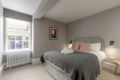a bedroom with a large bed and a window at JOIVY Luxurious Home near Haymarket Station in Edinburgh