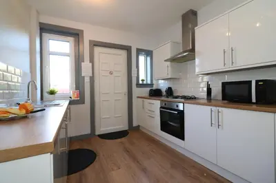 a kitchen with white cabinets and a black microwave at Signature - Burnbank House in Hamilton
