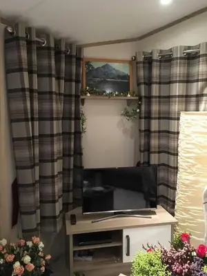 a living room with a tv and curtains at Shanthi Lodge in Dunning