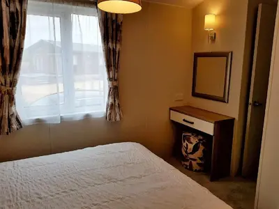 a bedroom with a bed and a mirror and a window at Shanthi Lodge in Dunning