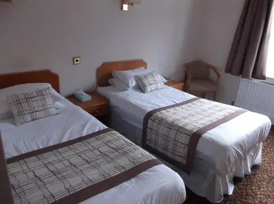 a hotel room with two beds and a chair at Arrochar Hotel 'A Bespoke Hotel' in Arrochar