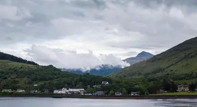 a town in a valley with mountains and a body of water at Arrochar Hotel 'A Bespoke Hotel' in Arrochar