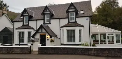 a white house with a black roof at Craigbank Guest House in Crianlarich