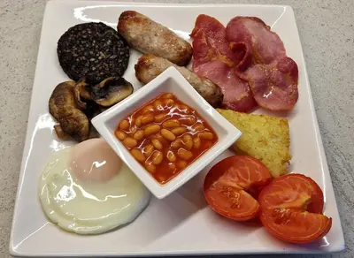 a plate of food with eggs bacon mushrooms and tomatoes at Craigbank Guest House in Crianlarich