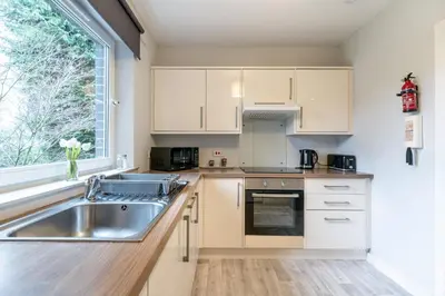 a kitchen with white cabinets and a sink and a window at Ground-fl Two Bedroom Apartment in Bridge of Allan in Bridge of Allan