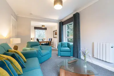 a living room with blue chairs and a table at Ground-fl Two Bedroom Apartment in Bridge of Allan in Bridge of Allan