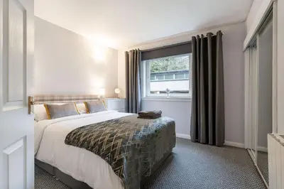 a bedroom with a large bed and a window at Ground-fl Two Bedroom Apartment in Bridge of Allan in Bridge of Allan