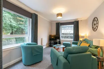 a living room with chairs and a couch and a tv at Ground-fl Two Bedroom Apartment in Bridge of Allan in Bridge of Allan