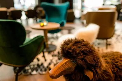 a stuffed animal sitting in a room with chairs and tables at Motel One Glasgow in Glasgow