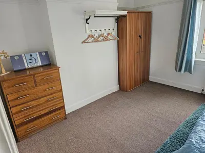 a bedroom with a bed and a dresser and a closet at Snug - Meadhan Apartment in Helensburgh