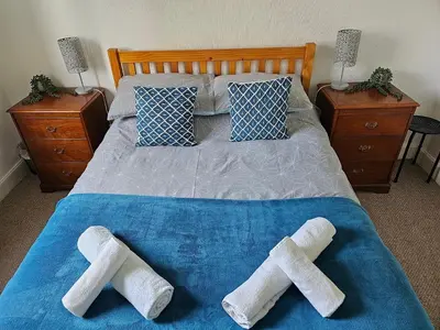 a bed with two pairs of knee and foot towels on it at Snug - Meadhan Apartment in Helensburgh