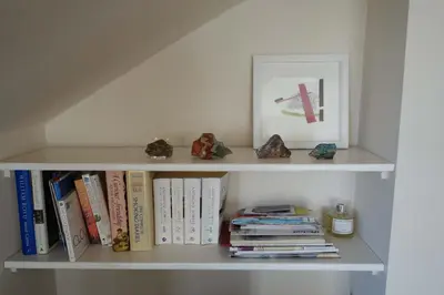a white book shelf with books and a picture at Sophisticated Edinburgh Apartment in City Centre in Edinburgh