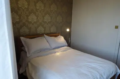 a bed with white pillows in a small room at Sophisticated Edinburgh Apartment in City Centre in Edinburgh