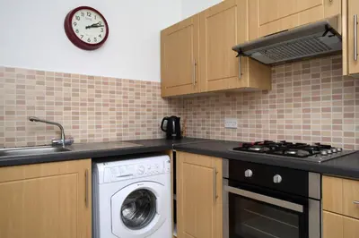 a kitchen with a washing machine and a clock on the wall at Stylish 2 Bedroom Bruntsfield Apartment in Edinburgh in Edinburgh