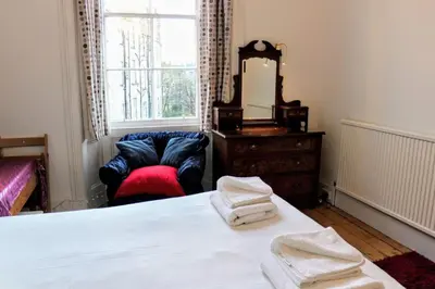 a bedroom with a bed and a chair and a mirror at Traditional Apartment oer the Meadows in Edinburgh
