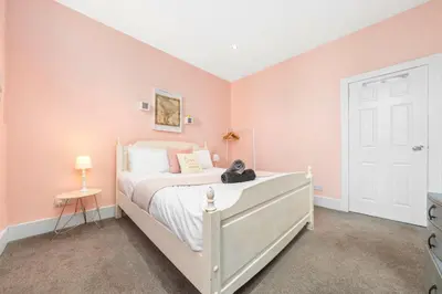 a bedroom with a white bed with a teddy bear on it at Unique Victorian Home in Glasgow in Glasgow