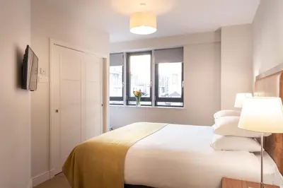 a white bedroom with a bed and a window at PREMIER SUITES PLUS Glasgow Bath Street in Glasgow