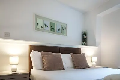 a bedroom with a bed with two lamps and two pictures on the wall at Glasgow City Flats in Glasgow