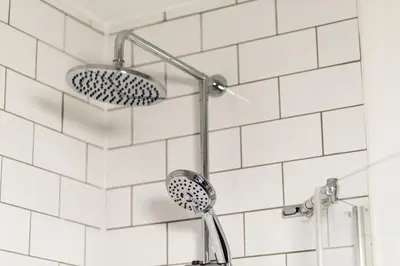 a shower head in a bathroom with white tiles at The Glencoe Inn in Glencoe