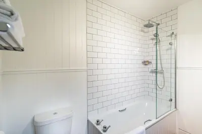 a white bathroom with a shower and a toilet at The Glencoe Inn in Glencoe