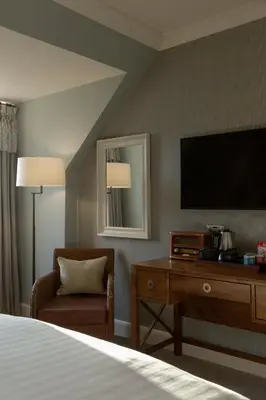 a hotel room with a bed and a tv and a chair at The Glencoe Inn in Glencoe