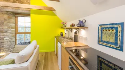 a kitchen with a couch and a yellow wall at Hayloft Edinburgh in Edinburgh