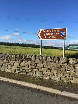 a sign on the side of a road next to a stone wall at Hayloft Edinburgh in Edinburgh