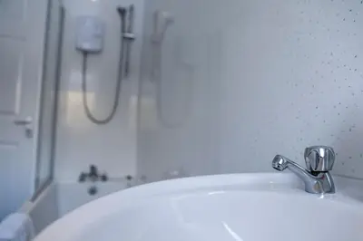 a bathroom with a white sink and a shower at Meadowburn View in Wishaw