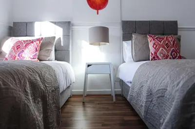 a bedroom with two beds and a side table at Meadowburn View in Wishaw
