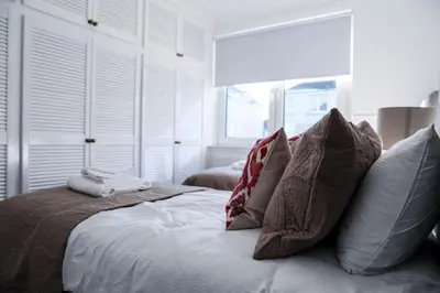 a white bedroom with a bed with pillows at Meadowburn View in Wishaw