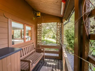 a wooden porch with a bench and a window at The Log Cabin in Kilmore