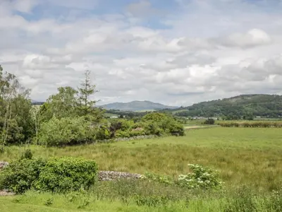 a field of grass with mountains in the distance at The Dairy in Newton Stewart