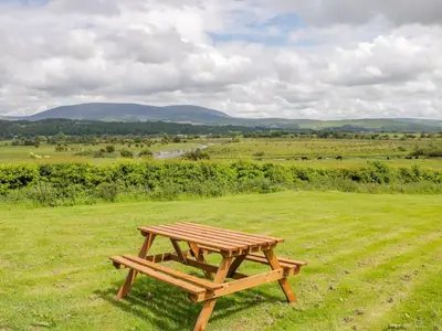 a wooden picnic table sitting in the middle of a field at The Byre in Newton Stewart