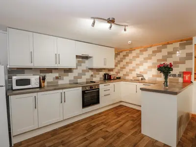 a kitchen with white cabinets and a counter top at The Byre in Newton Stewart