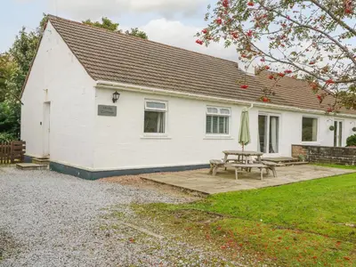 a white house with a picnic table and a patio at Holly Cottage in Glencoe