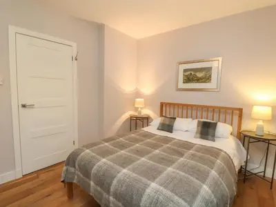 a bedroom with a bed and two tables with lamps at Holly Cottage in Glencoe