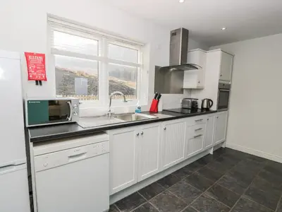 a kitchen with white cabinets and a sink and a window at Starfish Cottage in Craignure