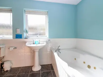 a bathroom with a tub and a sink and a bath tub at Starfish Cottage in Craignure