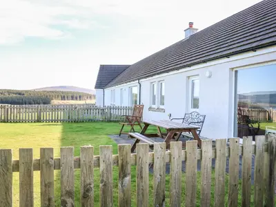 a white house with a bench and a fence at Starfish Cottage in Craignure