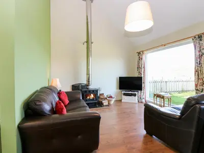 a living room with a leather couch and a fireplace at Driftwood Cottage in Craignure
