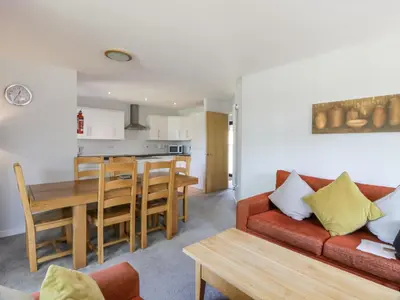 a living room and kitchen with a red couch and a table at Brunston Castle Lodge in Girvan