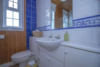 a bathroom with a sink and a toilet and a mirror at Craigievern Cottage in Drymen