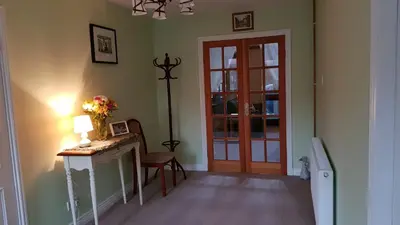 a room with a table and a door with a vase of flowers at The Old Cottage in Arduaine