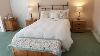 a bedroom with a large bed and two night stands at The Old Cottage in Arduaine