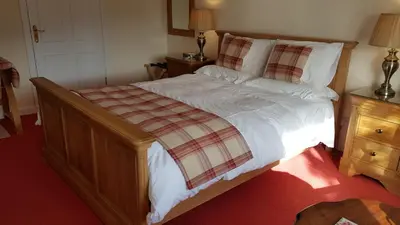 a bedroom with a bed with a plaid blanket on it at The Old Cottage in Arduaine