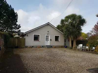a white house with a palm tree and a gravel driveway at Ardshiel Hotel in Campbeltown